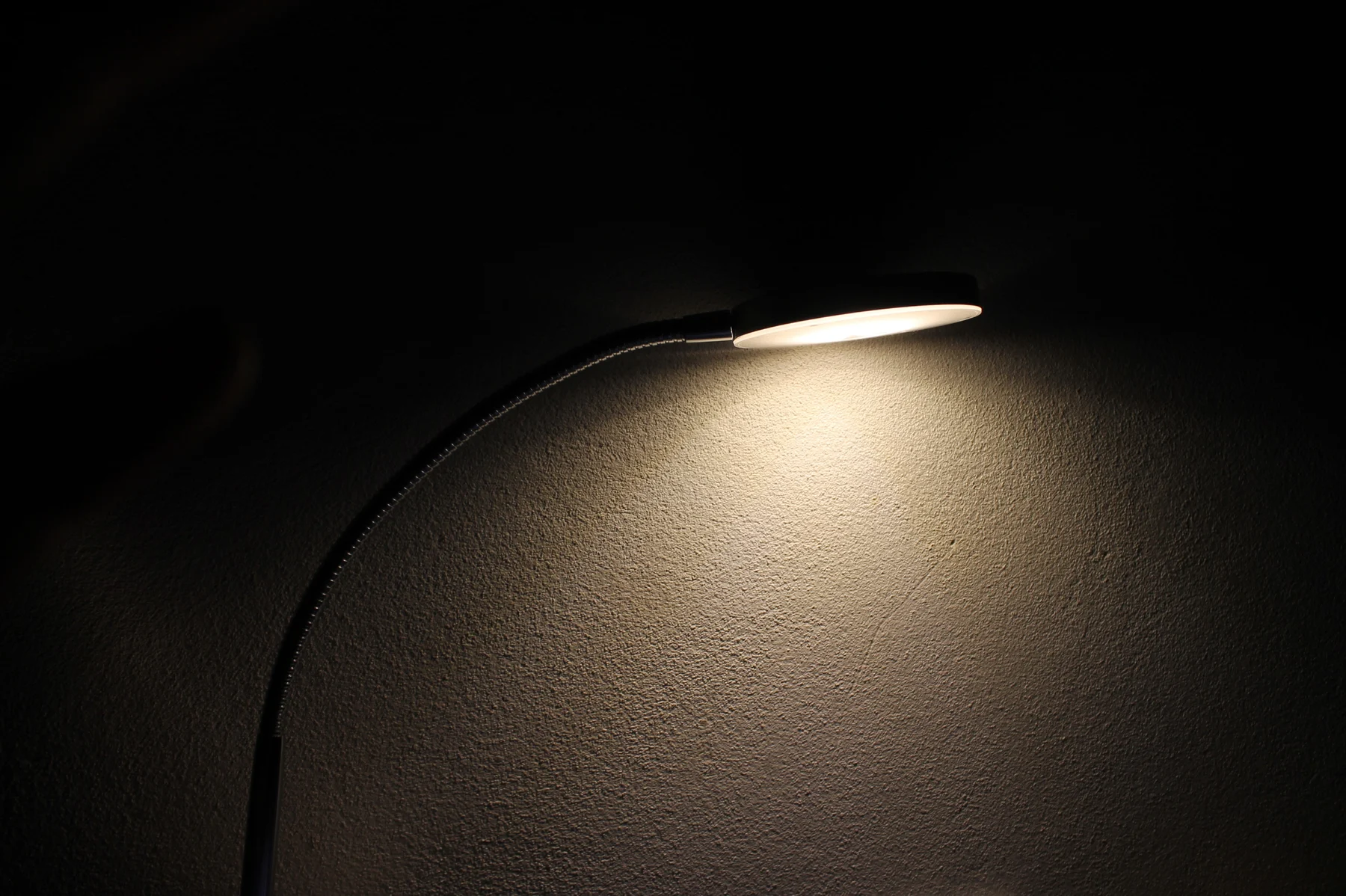 A single lamp casting light on a dark wall