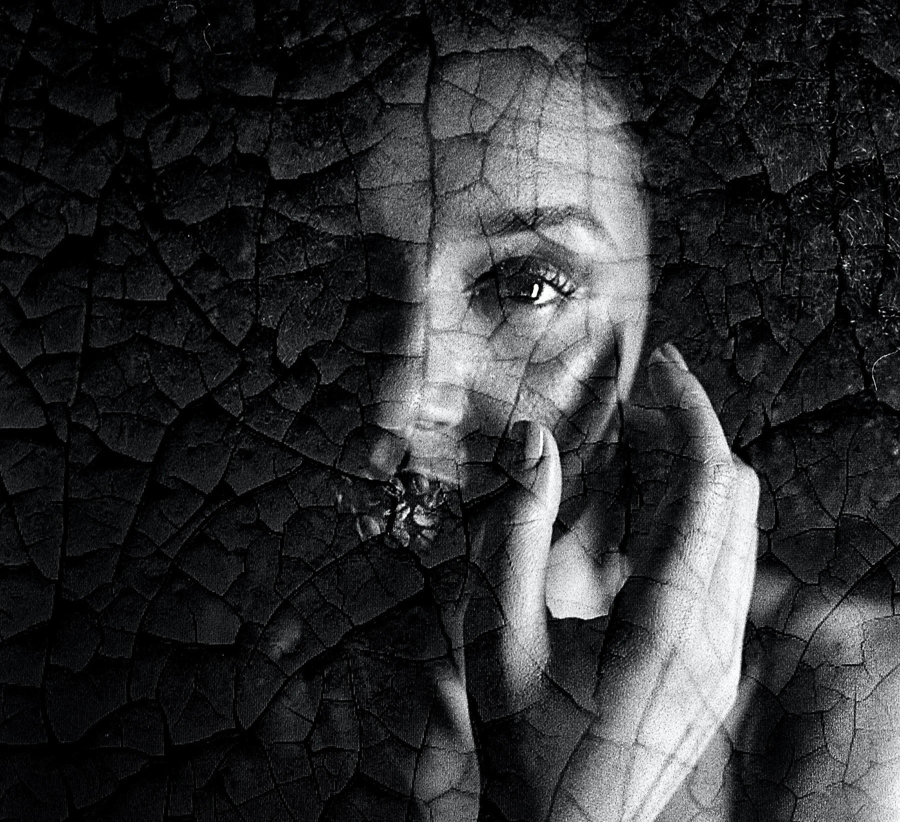 A face emerging through a cracked, dark surface