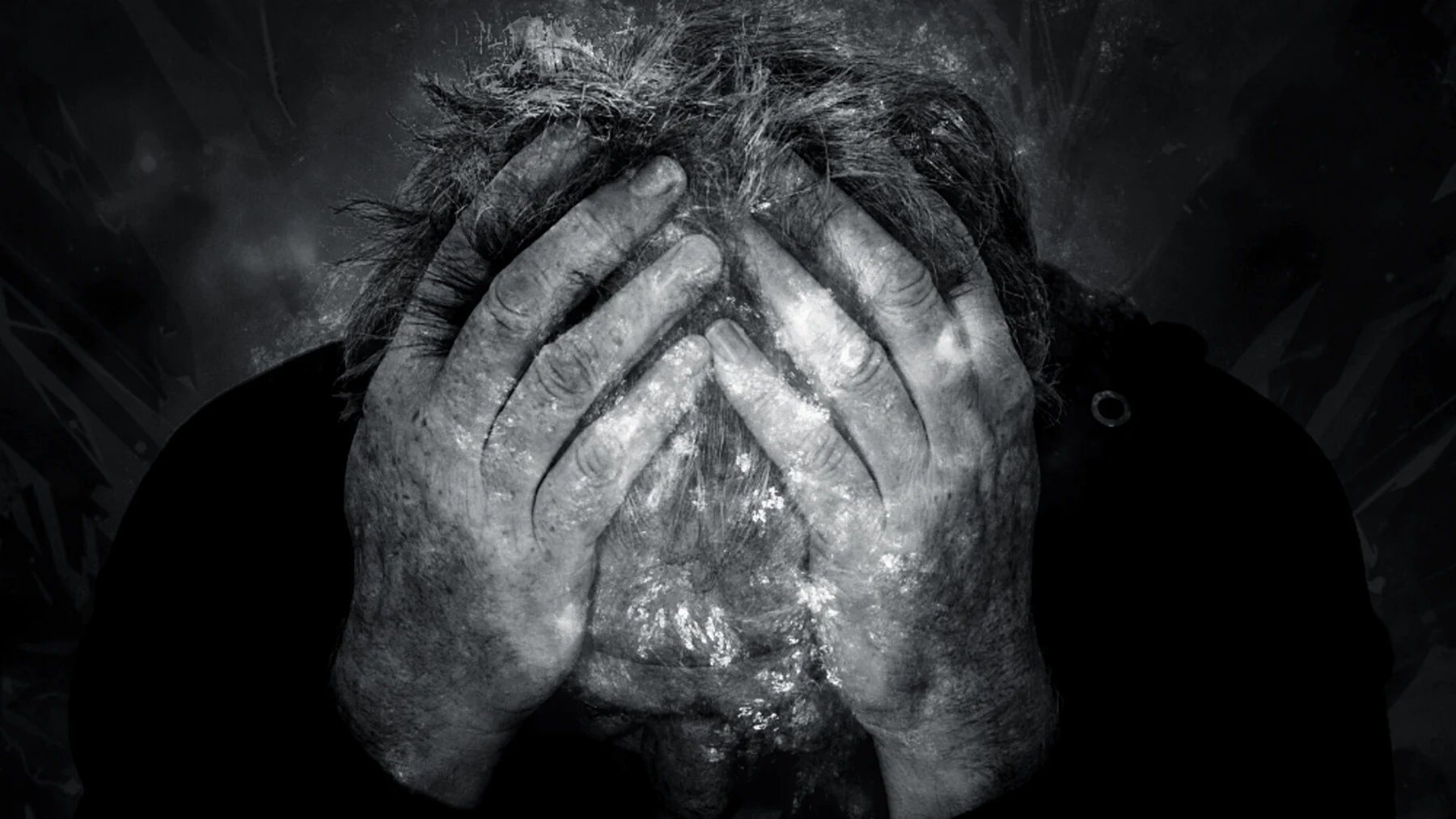 A person covering their face with both hands in black and white