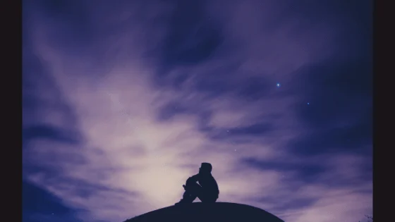A silhouetted figure beneath a purple evening sky