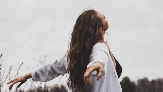 A woman reaching back to hold another person's hand outdoors