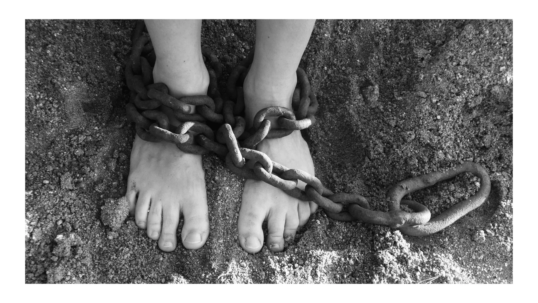 Bare feet bound by a heavy chain